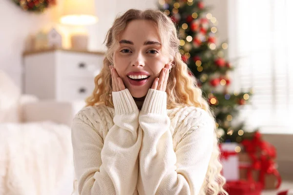 Evdeki bulanık ışıklara karşı süveter giymiş gülümseyen kadın portresi. Mutlu Noeller ve mutlu yıllar.