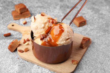 Karamel soslu lezzetli dondurma ve gri masada badem, yakın plan.