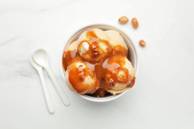 Karamel soslu lezzetli dondurma, badem ve beyaz masada patlamış mısır.