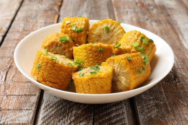 Ahşap masada yeşil soğanlı haşlanmış mısır koçanları, yakın plan.