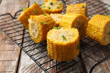 Ahşap masada yeşil soğanlı haşlanmış mısır koçanları, yakın plan.