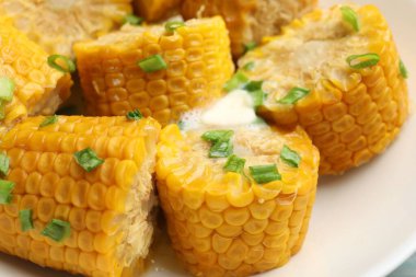 Kaynamış mısır koçanları ve yeşil soğan ve tereyağı, yakın plan.