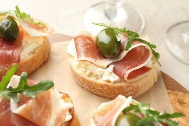 Krem peynirli nefis bruschettalar, prosciutto, yeşil zeytin ve roka masada, yakın plan.