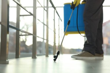 Böcek ilaçlama işçisi kapalı alanda böcek ilacı sıkıyor, yakın plan. Metin için boşluk