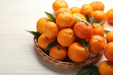 Beyaz ahşap masada taze mandalina ve yeşil yapraklar.