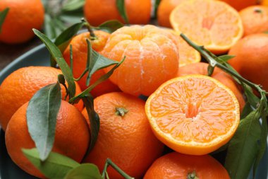 Taze mandalina ve yeşil yapraklar masada, yakın plan.