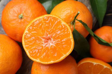 Taze mandalina ve yeşil yapraklar masada, düz yerde.