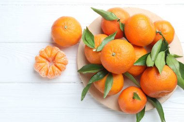 Taze mandalina ve yeşil yapraklar beyaz ahşap masada, düz yatıyordu.