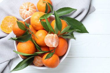 Beyaz ahşap masada taze mandalina ve yeşil yapraklar. Metin için boşluk