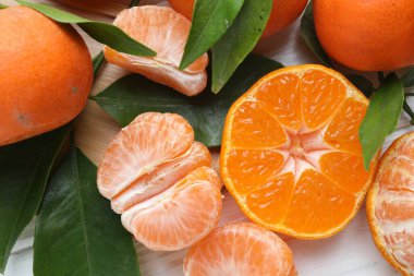 Taze mandalina ve yeşil yapraklar beyaz ahşap masada, düz yatıyordu.