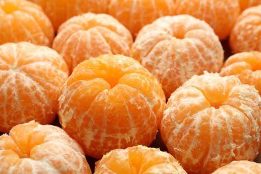 Arka plan olarak birçok olgun soyulmuş mandalina, yakın plan