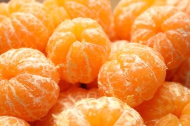 Arka plan olarak birçok olgun soyulmuş mandalina, yakın plan