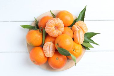 Taze taze mandalinalar, beyaz ahşap masa üzerinde yapraklar, üst manzara