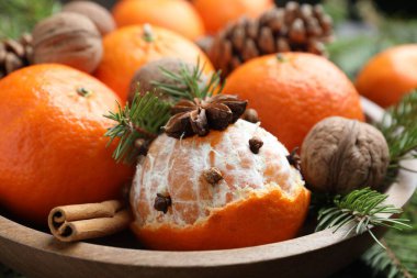 Olgun mandalinalar, baharatlar, cevizler, masada köknar ağacı dalları, yakın plan.