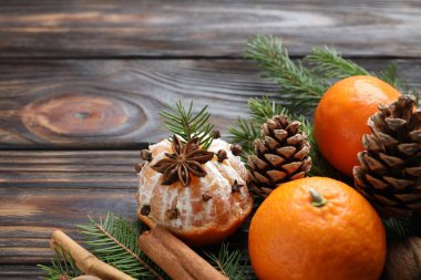 Olgun mandallar, baharatlar, köknar ağacı dalları ve tahta masa üzerindeki koniler, yakın plan. Metin için boşluk