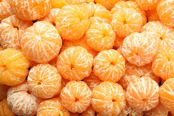 Arka plan olarak birçok olgun soyulmuş mandalina, üst görünüm