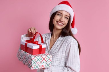 Noel Baba şapkalı mutlu kadın pembe arka planda hediyeler, mesaj için yer var.