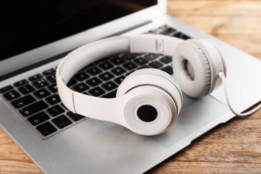 Kaliteli kulaklıklar ve dizüstü bilgisayarlar ahşap masada, yakın plan.