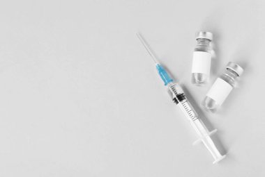 Gri arka planda aşı ve şırınga, düz yerde. Metin için boşluk