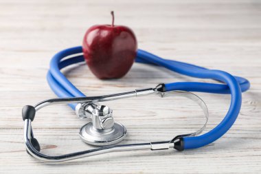 Olgun elma ve steteskop ahşap masada, yakın plan.