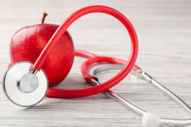 Olgun elma ve steteskop ahşap masada, yakın plan.