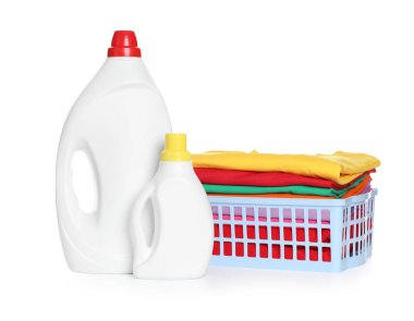 Çamaşır sepeti, temiz giysiler ve beyaza izole edilmiş deterjan şişeleri.