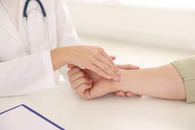 Doktor masadaki parmaklarıyla adamın nabzını kontrol ediyor.