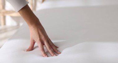 Yatakta yumuşak yatağa dokunan kadın, yakın plan.