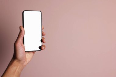 Dusty Rose arka planında boş ekranlı akıllı telefon tutan adam, yakın plan. Tasarım için model