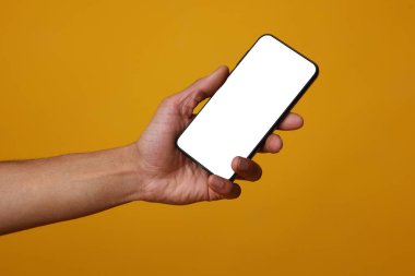 Turuncu arka planda boş ekranlı akıllı telefon tutan adam, yakın plan. Tasarım için model