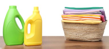 Çamaşır sepetinde beyaz arka planda çamaşır ve deterjan var.