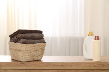 İçerideki ahşap dolapta havlu ve deterjan dolu çamaşır sepeti.