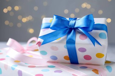 Gri arka planda güzel paketlenmiş hediyeler, bulanık ışıklar, yakın plan. Bokeh etkisi