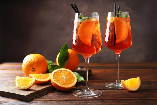 Serinletici spritzer kokteyli ve portakallar ahşap masada.