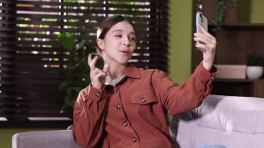 Genç kız evdeki kanepede selfie çekiyor.