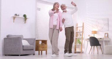 Mutlu yaşlı çift evde dans ediyor.