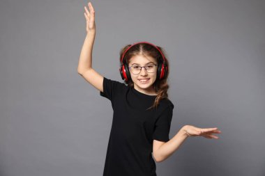 Kulaklıklı gülümseyen kızın portresi gri arka planda müzik dinliyor.