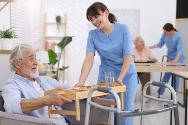 Huzurevinde yaşlılara yemek servisi yapan bakım işçisi.