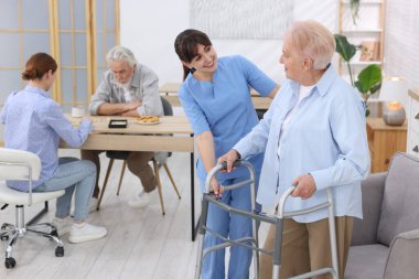 Huzurevinde yaşlı kadına Walker 'la yardım eden bakım işçisi.