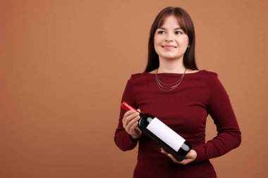 Soluk kahverengi arka planda kırmızı şarap şişesi olan profesyonel şarap garsonu.