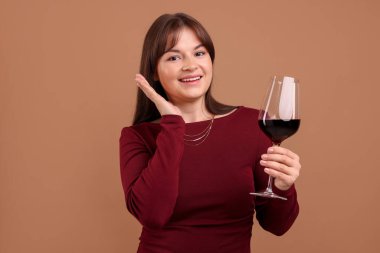 Soluk kahverengi arka planda kırmızı şarap kadehi olan profesyonel şarap garsonu.