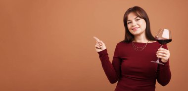 Soluk kahverengi arka planda kırmızı şarap kadehi olan profesyonel şarap garsonu.