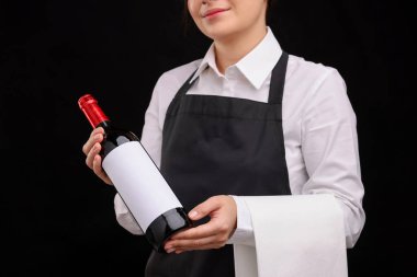 Siyah arka planda kırmızı şarap şişesi olan profesyonel şarap garsonu.