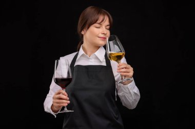 Profesyonel şarap garsonu siyah arka planda şarap tadıyor.