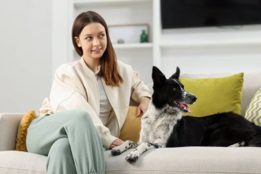 Evdeki kanepesinde Collie köpeği olan bir kadın.