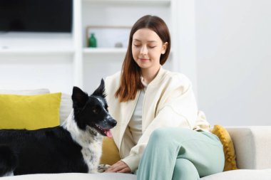 Evdeki kanepesinde Collie köpeği olan bir kadın.