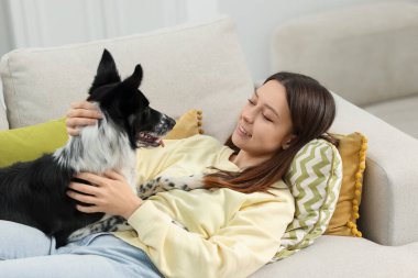 Evdeki kanepesinde Collie köpeği olan bir kadın.