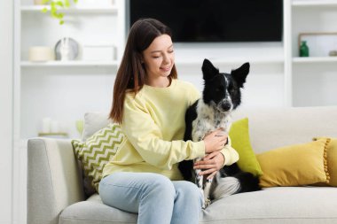 Evdeki kanepesinde Collie köpeği olan bir kadın.