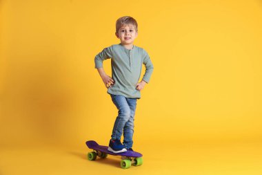 Sarı arka planda para tahtasıyla gülümseyen küçük çocuk.