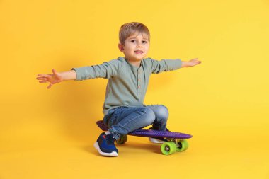 Sarı arka planda para tahtasıyla gülümseyen küçük çocuk.